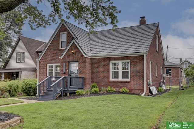 view of front of home featuring a front lawn, fence, a chimney, and brick siding