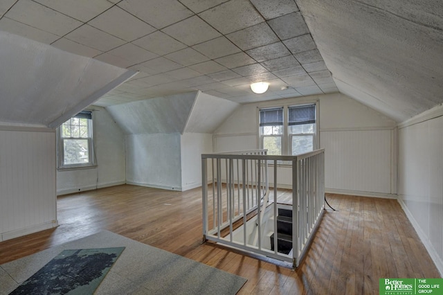 additional living space featuring lofted ceiling, hardwood / wood-style flooring, and baseboards