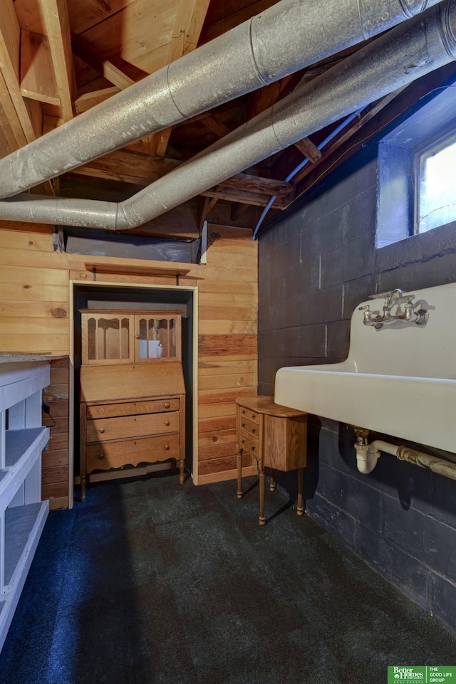 basement featuring dark colored carpet, wooden walls, and concrete block wall