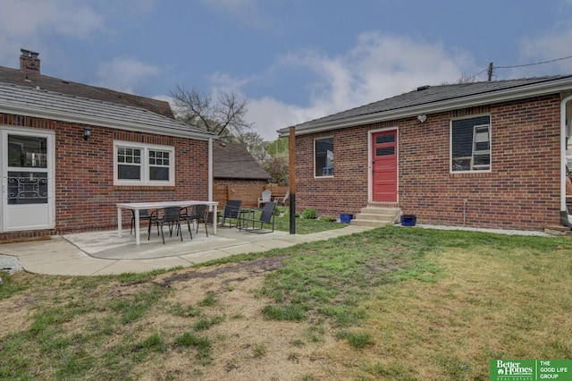 rear view of house featuring a lawn, a patio area, entry steps, and brick siding
