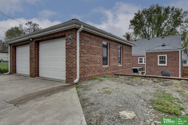 view of side of property with driveway, a chimney, and brick siding