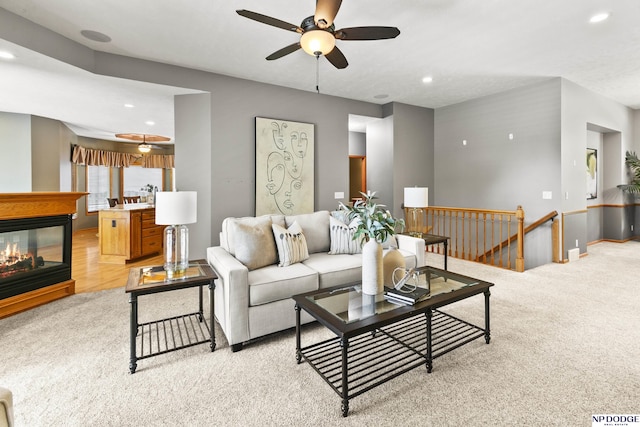 living room with ceiling fan, light carpet, recessed lighting, a multi sided fireplace, and baseboards