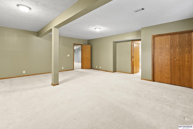 finished below grade area featuring light colored carpet, a textured ceiling, and baseboards