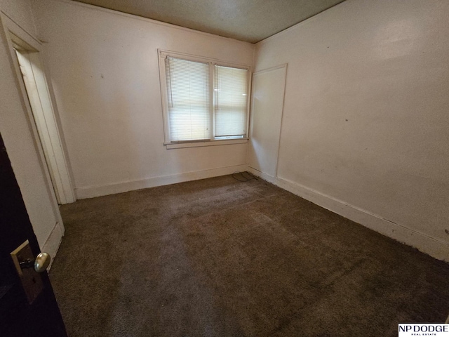 unfurnished room featuring dark colored carpet and baseboards
