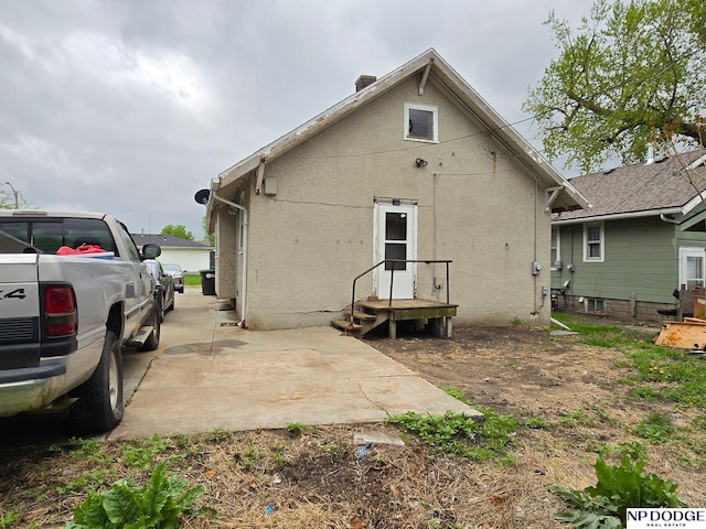 rear view of house featuring stucco siding