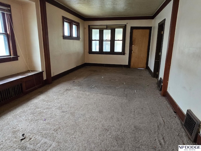 carpeted spare room with baseboards, visible vents, and ornamental molding