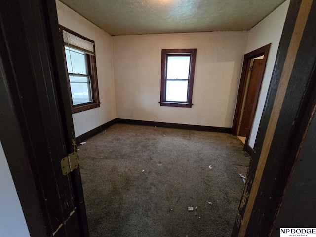 carpeted spare room with baseboards and a textured ceiling
