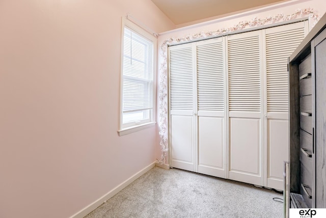 unfurnished bedroom with baseboards, light carpet, and a closet