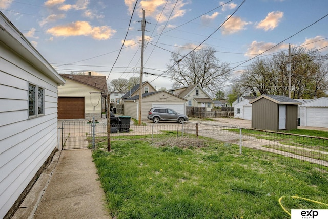 view of yard with a detached garage, fence, a residential view, and an outbuilding