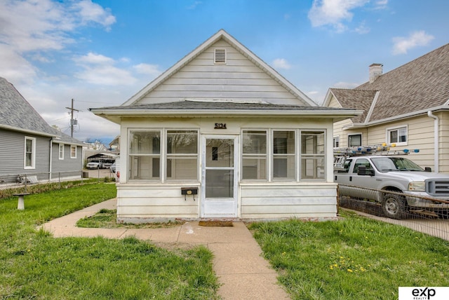 shotgun-style home featuring a front yard and a sunroom
