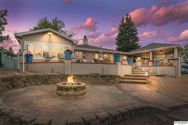 back of property featuring an outdoor fire pit, a patio area, stucco siding, and a chimney