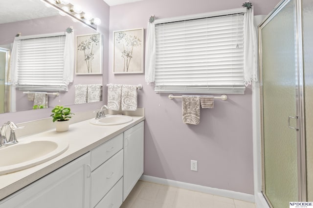 full bathroom with a sink, a stall shower, double vanity, and baseboards