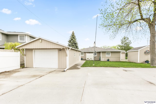view of front of home featuring driveway, an outbuilding, fence, a garage, and a front lawn
