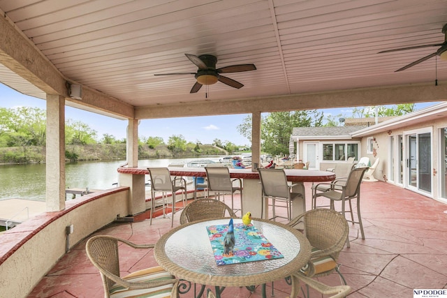 view of patio / terrace featuring a ceiling fan, outdoor dining space, and a water view