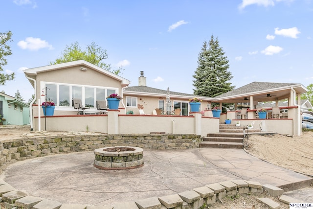 rear view of property featuring a patio area, stucco siding, a fire pit, and a ceiling fan