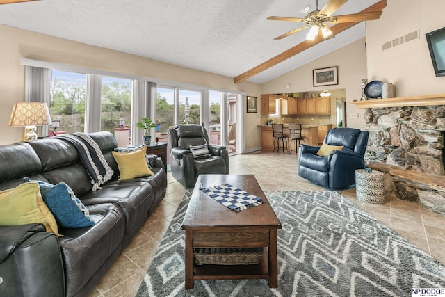 living room with a ceiling fan, high vaulted ceiling, a textured ceiling, visible vents, and light tile patterned flooring