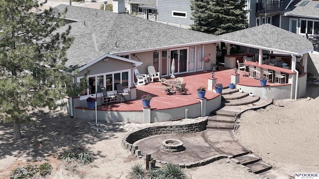 rear view of property with an outdoor fire pit, a wooden deck, a shingled roof, outdoor dry bar, and a patio area