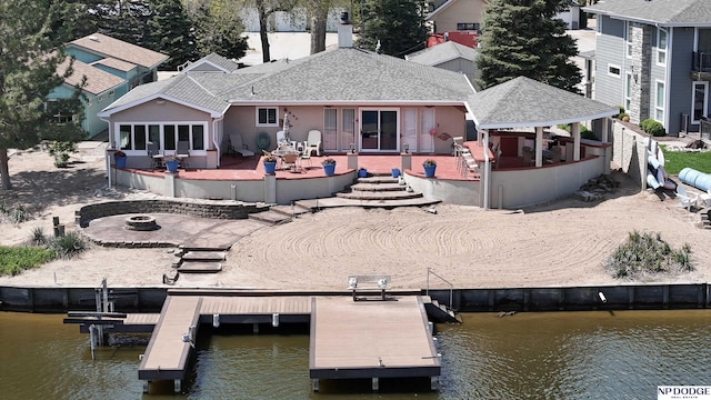 back of property with a fire pit, a patio, and a deck with water view