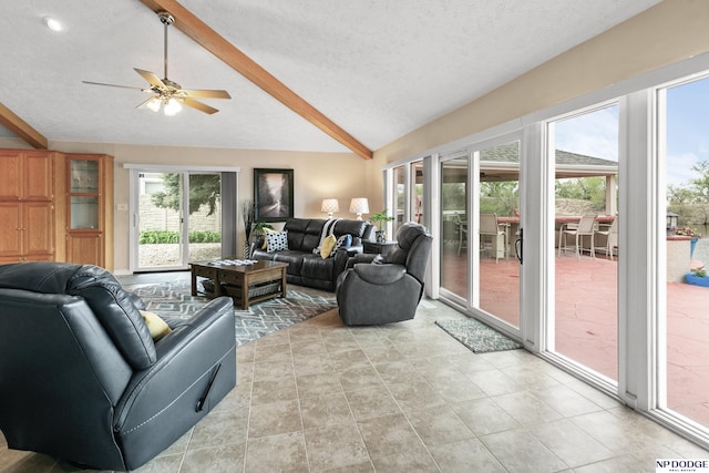 living room with a ceiling fan, lofted ceiling with beams, and a textured ceiling