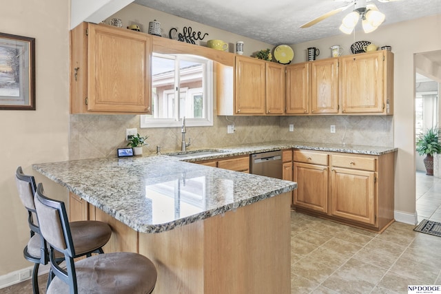 kitchen featuring stainless steel dishwasher, a healthy amount of sunlight, a sink, and a kitchen bar