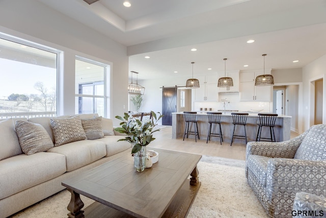 living area with a barn door, recessed lighting, and light wood-style flooring