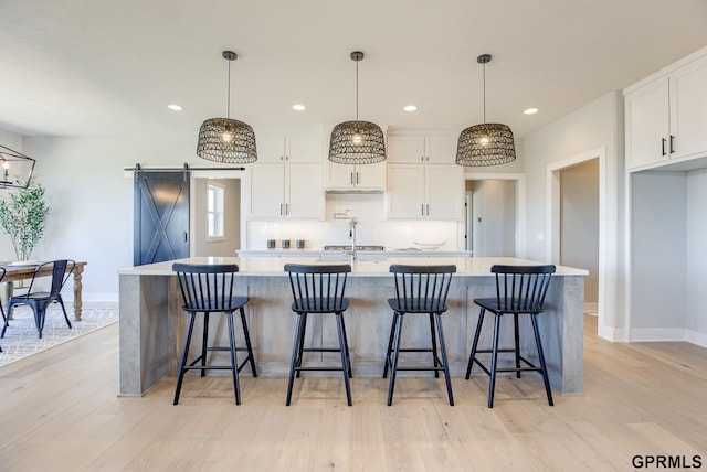kitchen with a barn door, tasteful backsplash, light countertops, and baseboards