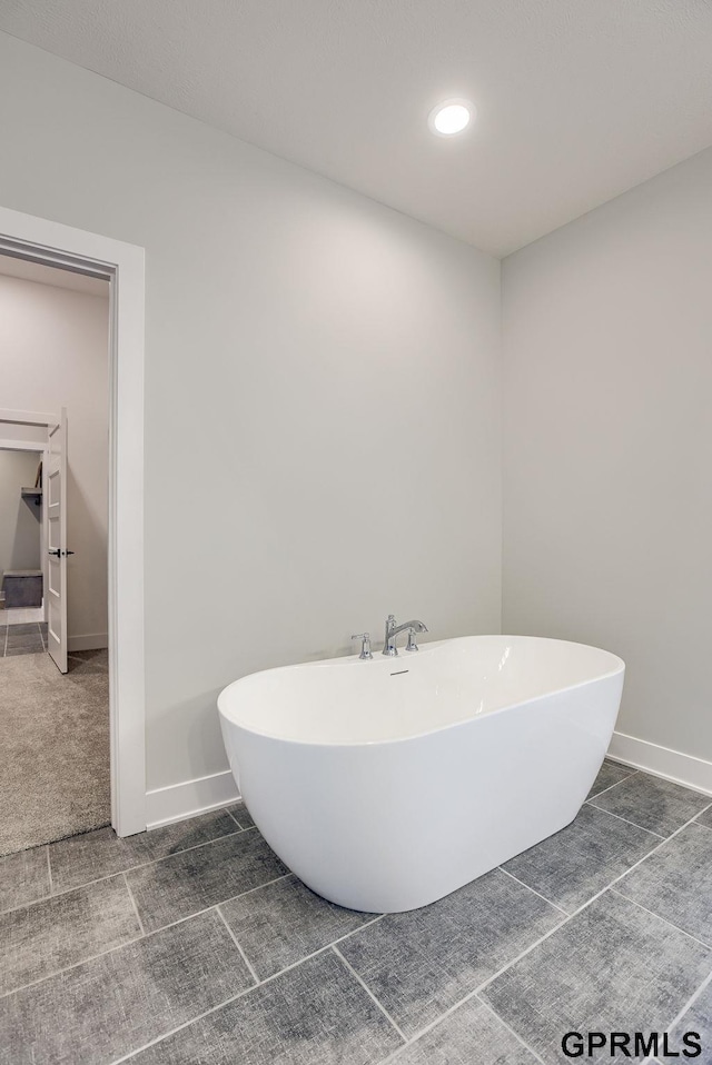 full bathroom featuring a soaking tub, baseboards, and recessed lighting