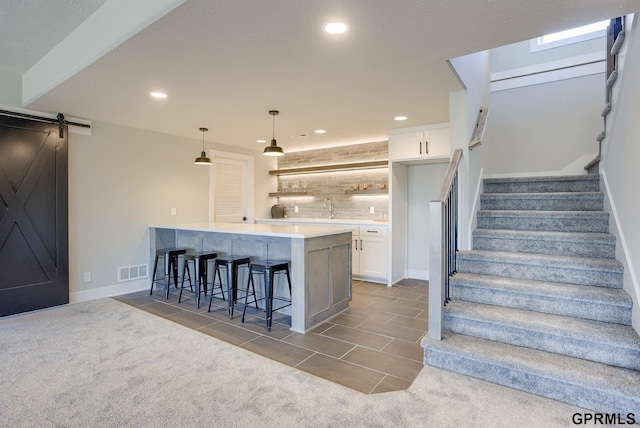 kitchen with a breakfast bar area, visible vents, white cabinets, and backsplash
