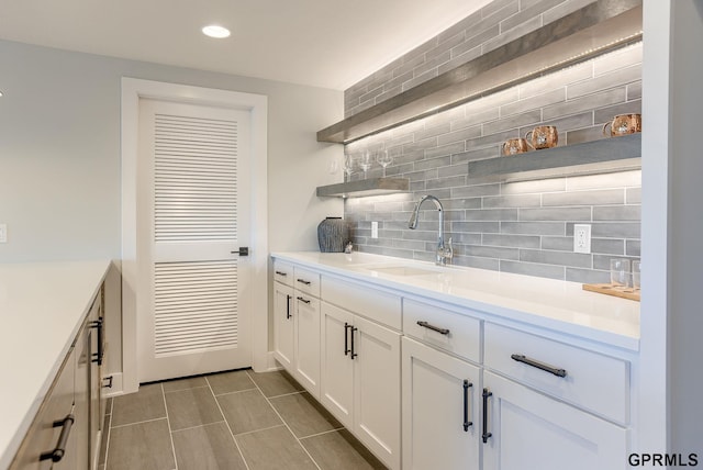 interior space featuring recessed lighting, backsplash, indoor wet bar, and a sink