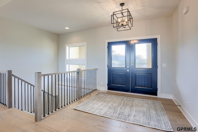 entryway featuring an inviting chandelier, wood finished floors, french doors, and baseboards