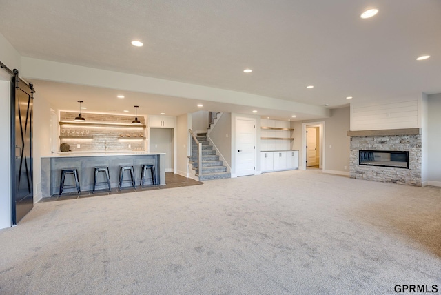 unfurnished living room with carpet flooring, a barn door, indoor bar, and recessed lighting