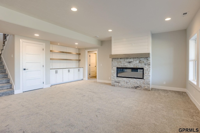 unfurnished living room with light colored carpet, recessed lighting, and stairs