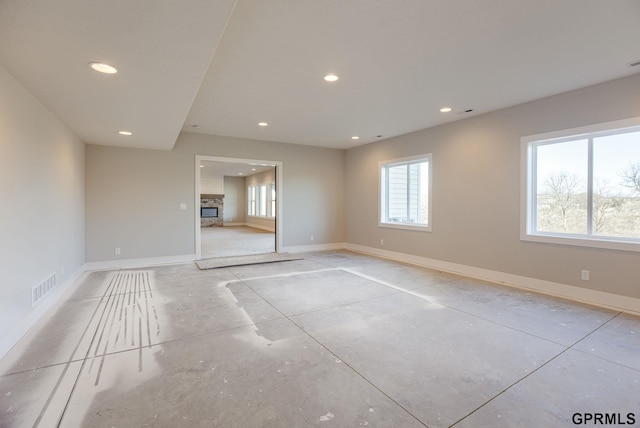 unfurnished room with recessed lighting, visible vents, a glass covered fireplace, and baseboards