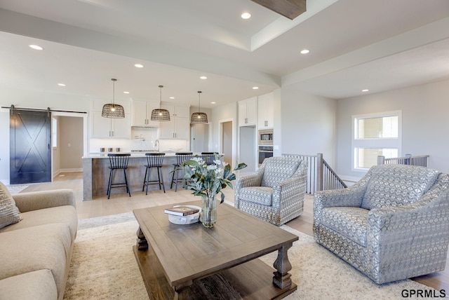 living area with recessed lighting, light wood finished floors, and a barn door