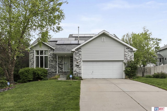 ranch-style house with roof with shingles, fence, concrete driveway, roof mounted solar panels, and a front lawn