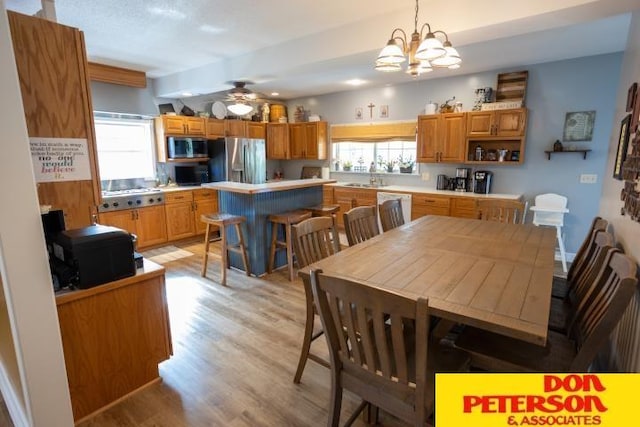 dining area featuring light wood-style floors, ceiling fan with notable chandelier, and a wealth of natural light