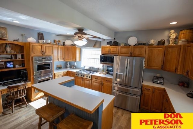 kitchen featuring light wood-style floors, light countertops, a kitchen breakfast bar, stainless steel appliances, and a ceiling fan