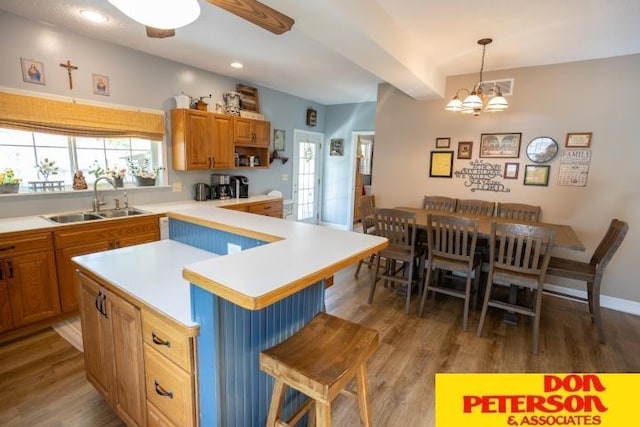 kitchen featuring light countertops, a sink, wood finished floors, and a kitchen bar