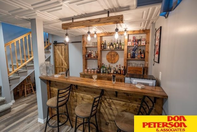 bar featuring an ornate ceiling, a dry bar, stairs, and wood finished floors