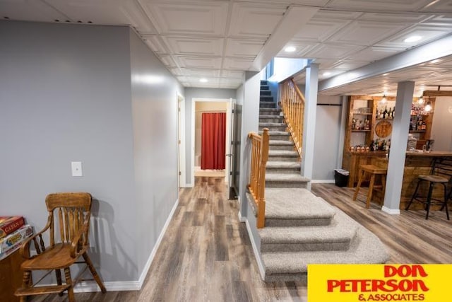 corridor with stairs, baseboards, wood finished floors, and an ornate ceiling
