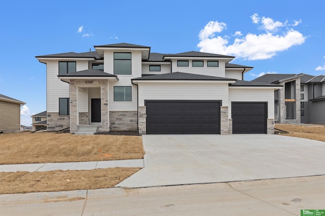 prairie-style house featuring a garage, concrete driveway, and stone siding