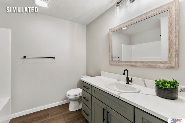 bathroom featuring a textured ceiling, wood finished floors, baseboards, vanity, and toilet