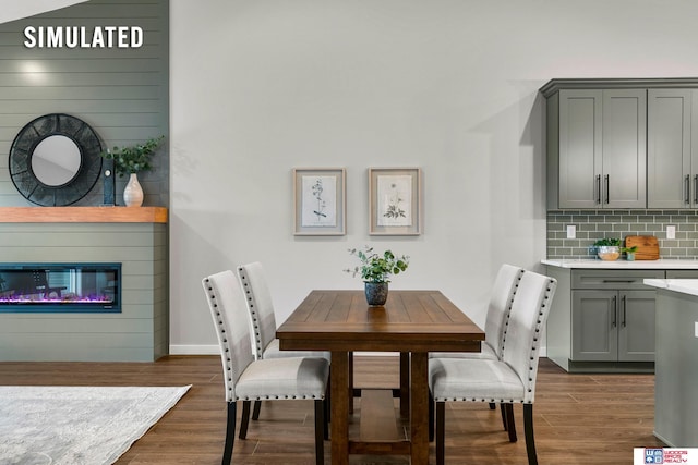 dining area featuring a large fireplace, baseboards, and dark wood-type flooring