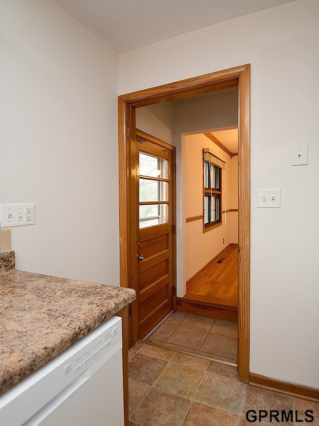 hall featuring baseboards and stone finish floor