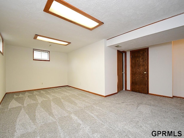 carpeted empty room with baseboards, a textured ceiling, and visible vents