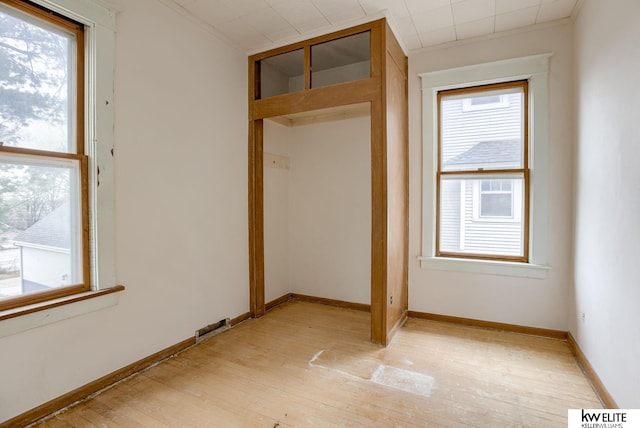 spare room featuring a wealth of natural light, light wood-style flooring, and baseboards