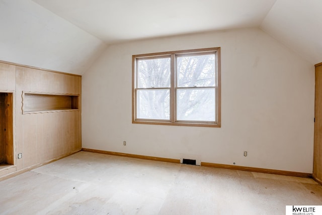 additional living space featuring baseboards, visible vents, built in shelves, and vaulted ceiling