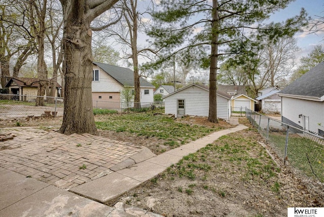 view of yard with a residential view, a detached garage, fence private yard, and a patio area