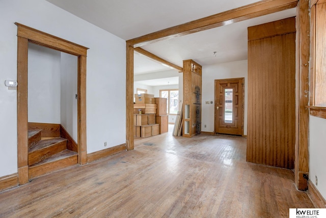 foyer with light wood-style floors, baseboards, and stairs