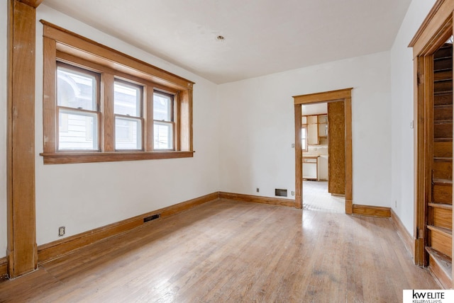 unfurnished room featuring light wood-style floors, visible vents, and baseboards